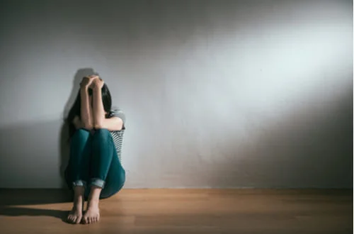 Женщина сидит на фоне серой стены